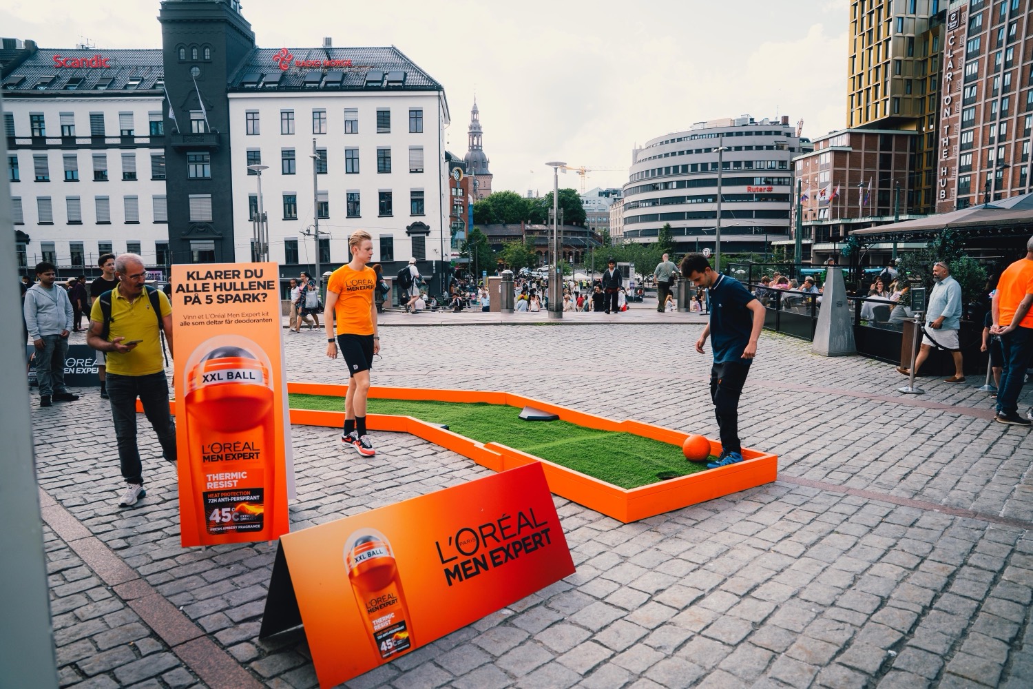Full square context — gameplay, signage and onlookers at Jernbanetorget.